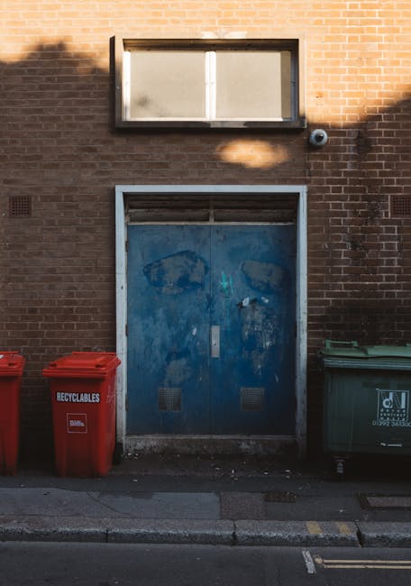 The image depicts a small group of four blue plastic rubbish bags stacked on a concrete step outside a building. The bags appear to be filled with waste, with some loosely gathered and tied at the top